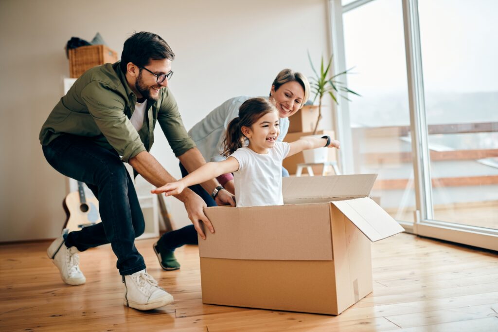 A happy family playing with a carton in their new home